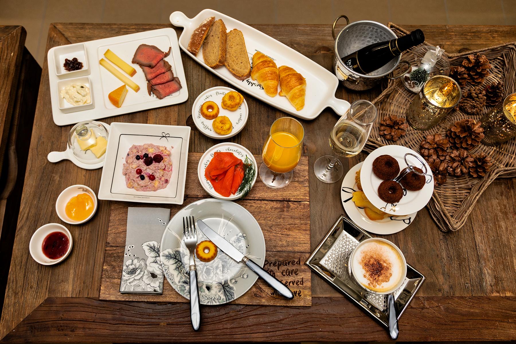 Gedeckter Frühstückstisch von oben: Gipfeli, Brot, Käse, Roastbeef, Räucherlachs, Müsli, Orangensaft, Prosecco und Cappuccino